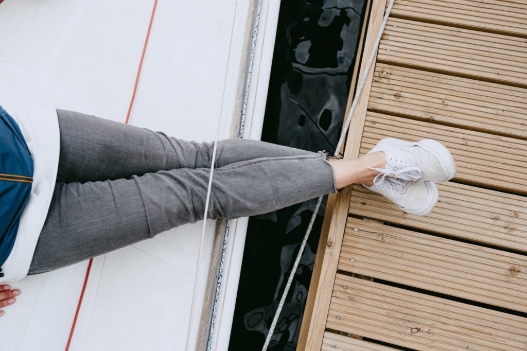 person in gray denim jeans and white sneakers standing on white wooden door